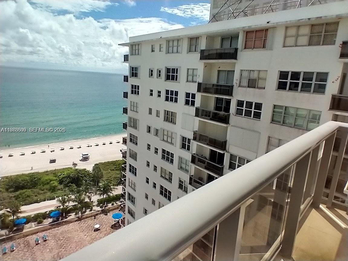 A high-angle view shows a beach, ocean, and a multi-story residential building from a balcony — 6039 Collins Ave # 1710, Miami Beach FL 33140, MIAMI BEACH, FL