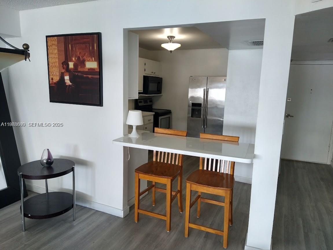 A kitchen with stainless steel appliances is visible behind a white breakfast bar with stools — 6039 Collins Ave # 1710, Miami Beach FL 33140, MIAMI BEACH, FL