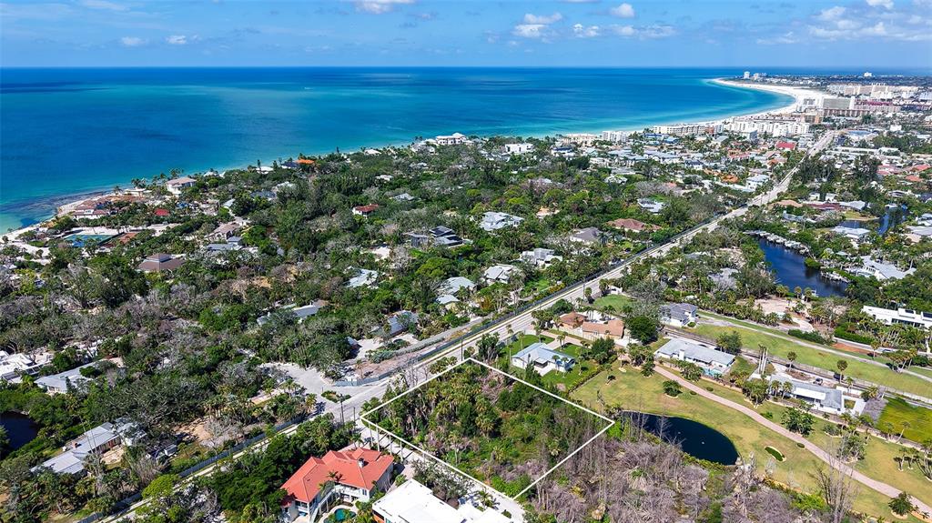 An aerial view shows a vacant, wooded lot outlined in white near a coastal residential area — 7401-A MIDNIGHT PASS ROAD UNIT A, SARASOTA, FL