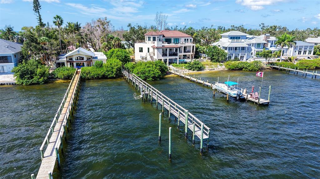 An aerial view shows three waterfront houses with private docks extending into the bay — 7401-A MIDNIGHT PASS ROAD UNIT A, SARASOTA, FL