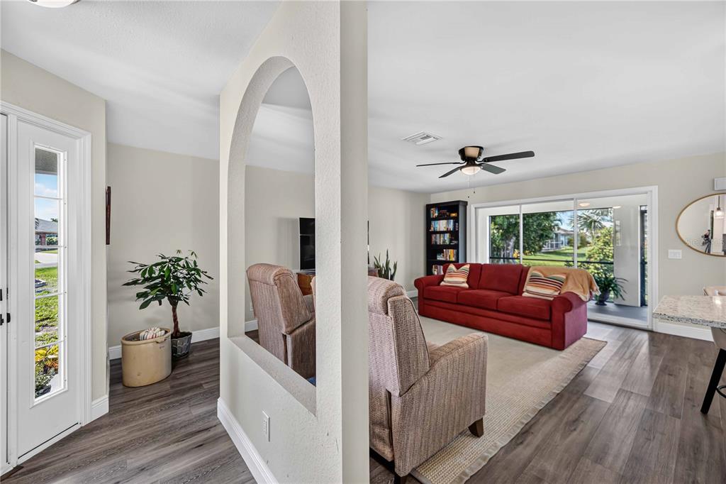 A living room features a red sofa, a beige armchair, and an arched wall cutout — 23 BUNKER PLACE, ROTONDA WEST, FL
