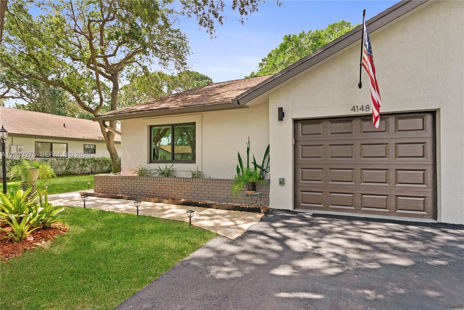 A single-story house features a brown garage door, a brick planter, and a paved walkway — 4148 N Palm Forest Dr N, Delray Beach FL 33445, DELRAY BEACH, FL
