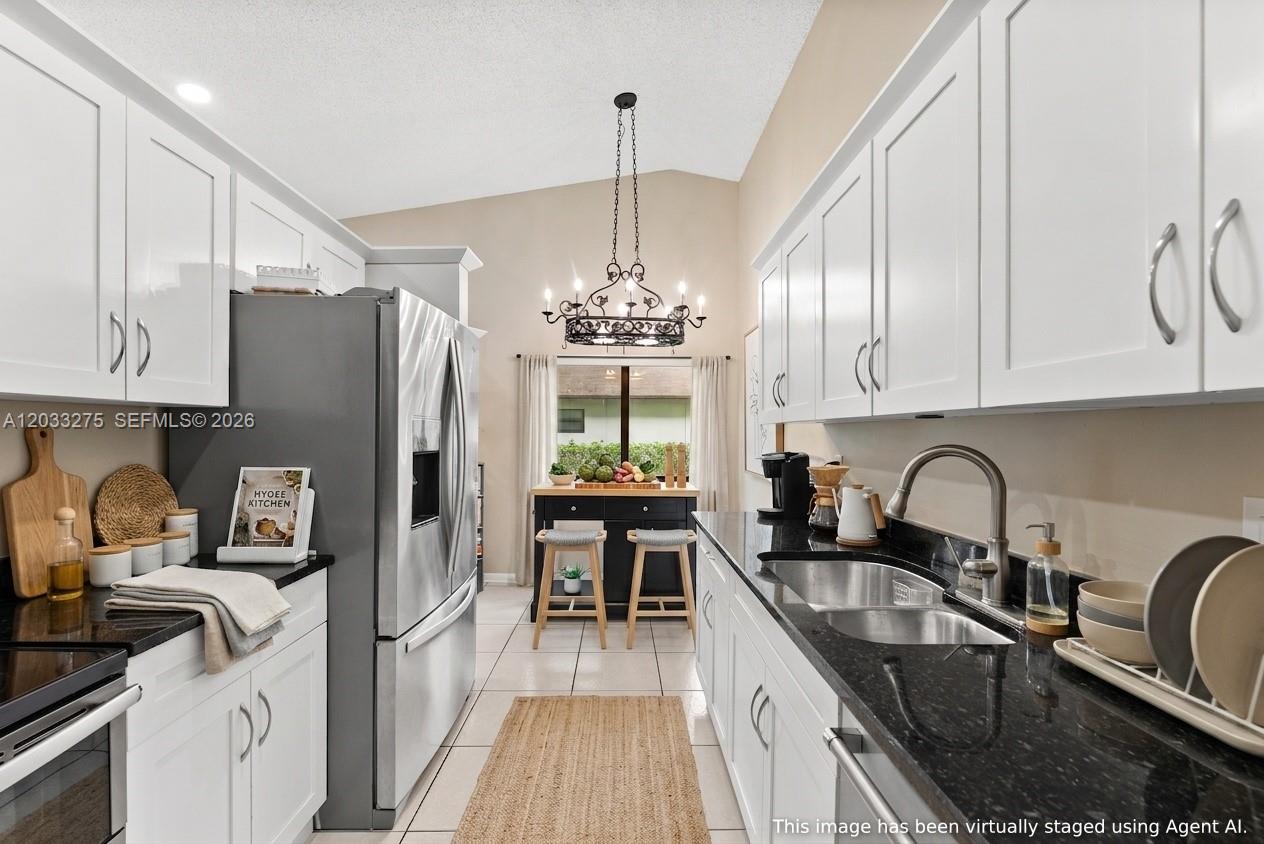 A galley kitchen features white cabinets, black granite countertops, stainless steel appliances, and a dining nook — 4148 N Palm Forest Dr N, Delray Beach FL 33445, DELRAY BEACH, FL