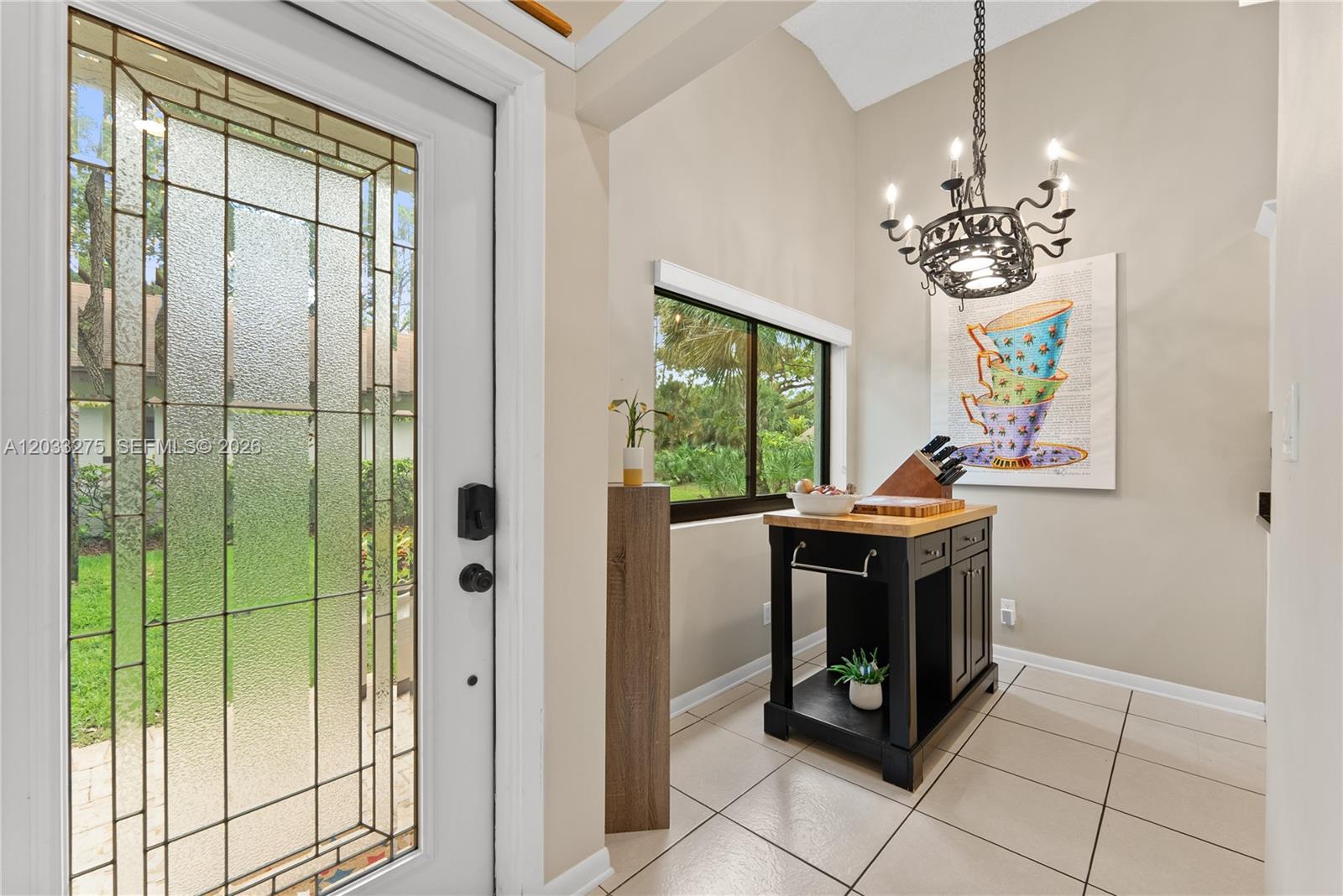 An entryway features a glass-paneled door, tile flooring, a kitchen island, and a decorative chandelier — 4148 N Palm Forest Dr N, Delray Beach FL 33445, DELRAY BEACH, FL