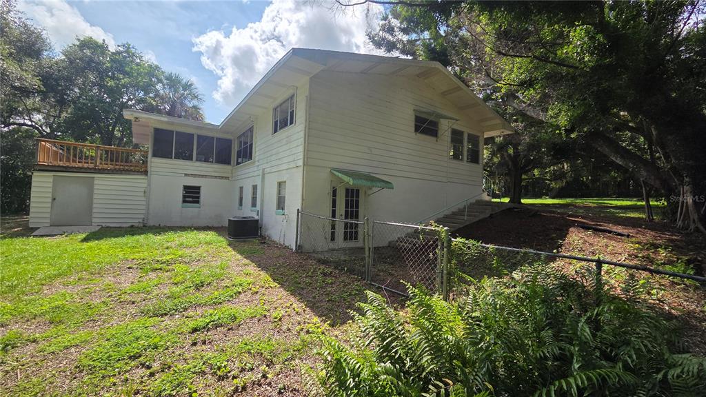 The exterior of a two-story white house features a wooden deck and a chain-link fence — 205 CATHERINE AVENUE, BABSON PARK, FL