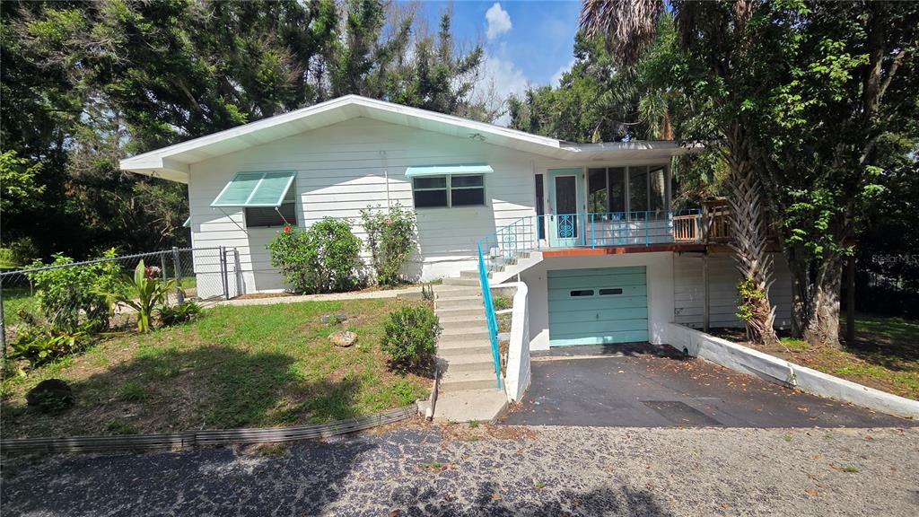 A white, single-story house features a front-facing garage, a raised porch, and a concrete staircase — 205 CATHERINE AVENUE, BABSON PARK, FL
