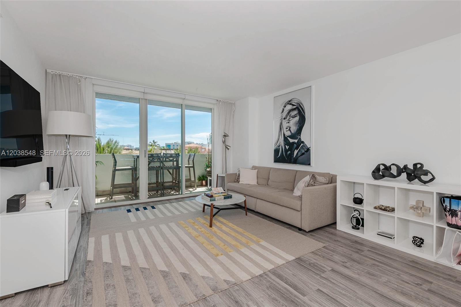 A living room features a beige sofa, a patterned area rug, and a balcony view — 90 Alton Rd # 607, Miami Beach FL 33139, MIAMI BEACH, FL