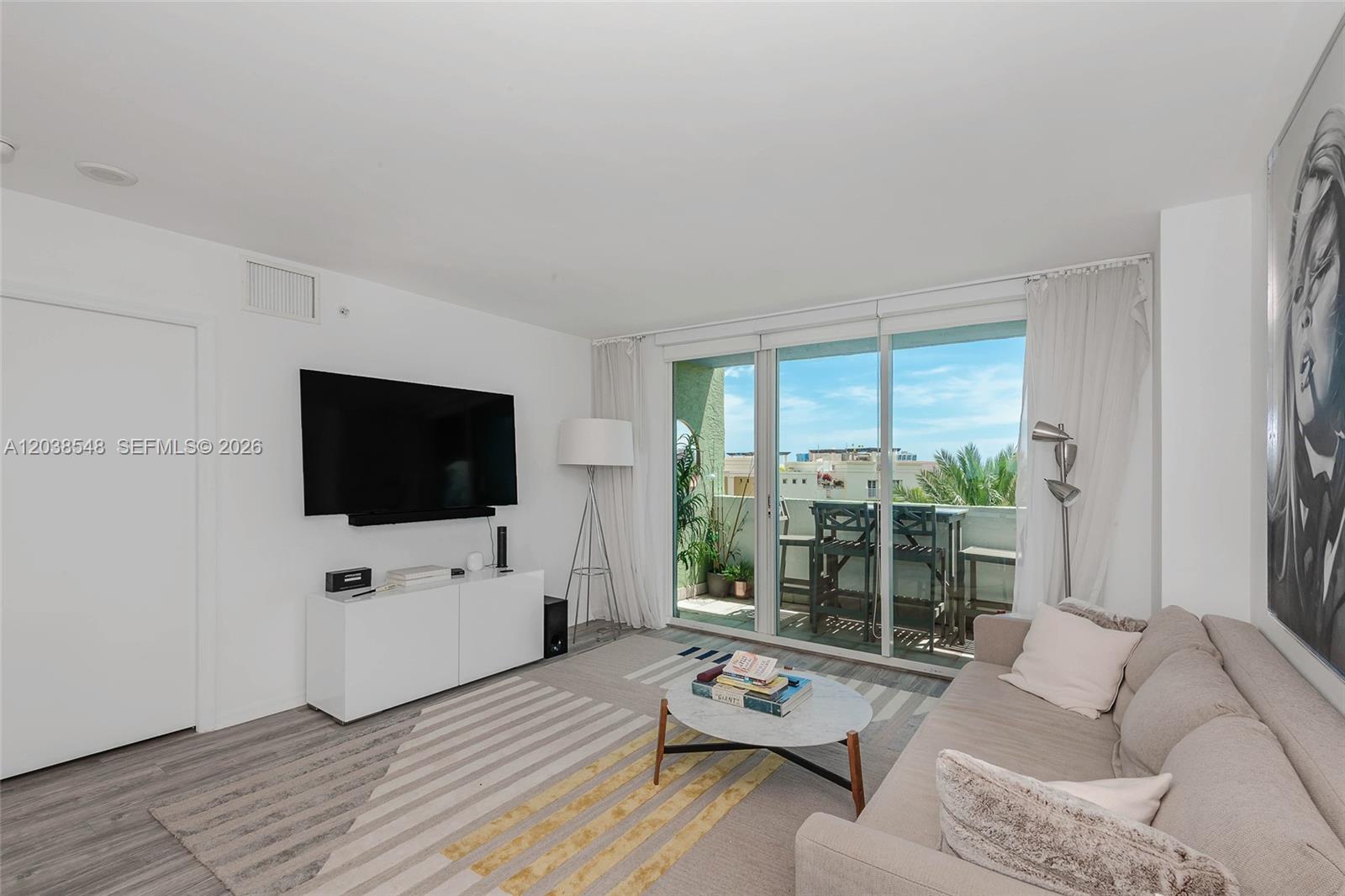 A living room features a television, a sofa, a coffee table, and a balcony view — 90 Alton Rd # 607, Miami Beach FL 33139, MIAMI BEACH, FL