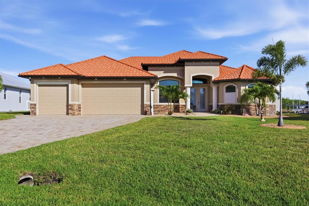 A single-story house with a tile roof, tan stucco exterior, and a three-car garage — 9266 MIGUE CIRCLE, PORT CHARLOTTE, FL
