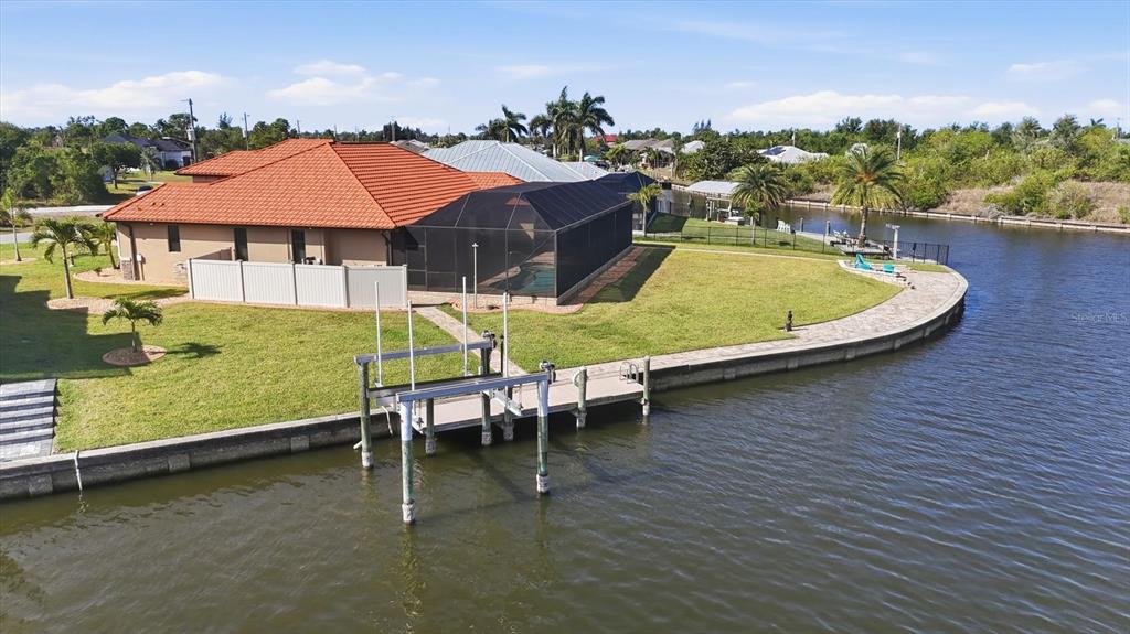 An aerial view of a waterfront house with a red tile roof and boat lift — 9266 MIGUE CIRCLE, PORT CHARLOTTE, FL
