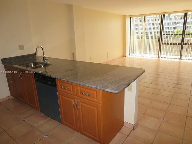 A kitchen with wood cabinets and granite countertops overlooks an empty room with tile floors — 600 NE 36th St # 517, Miami FL 33137, MIAMI, FL