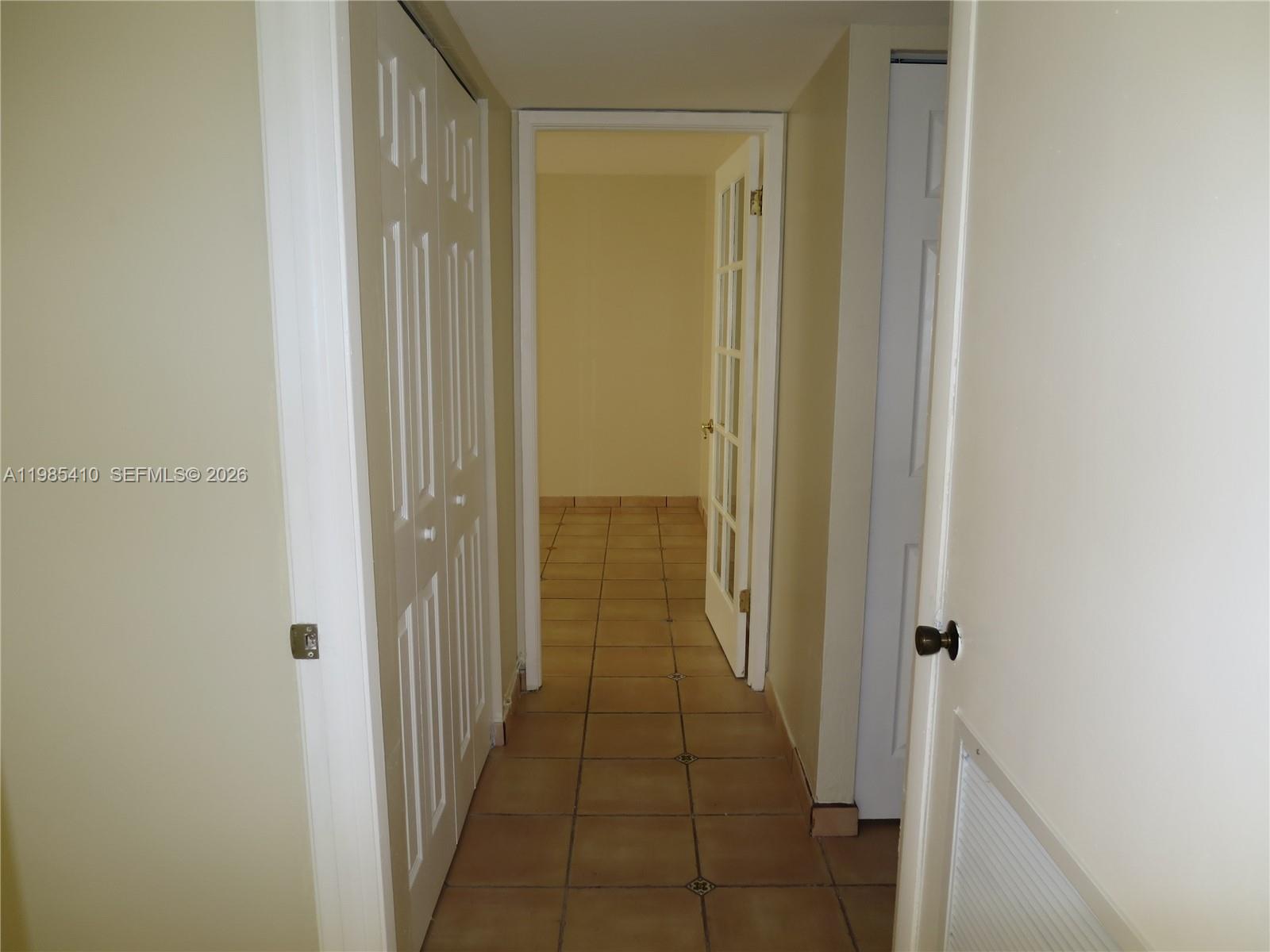 A hallway with tiled floors leads to an open doorway with a glass-paneled door — 600 NE 36th St # 517, Miami FL 33137, MIAMI, FL