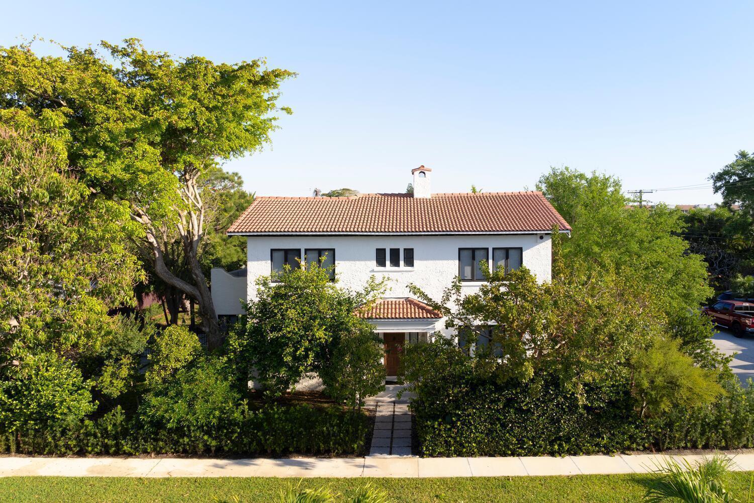 A two-story white stucco house with a red tile roof sits behind lush green landscaping — 1629 S Lakeside Drive, FL 33460, FL