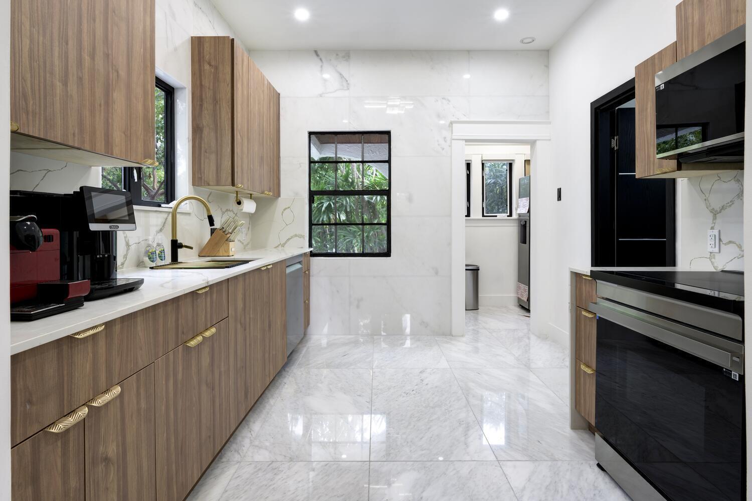 A galley kitchen features wood-grain cabinets, white marble countertops, and large-format marble floor tiles — 1629 S Lakeside Drive, FL 33460, FL