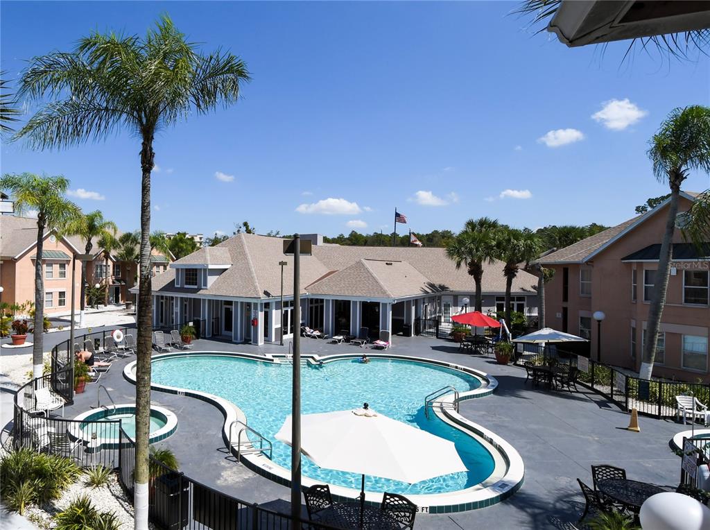 An outdoor swimming pool and hot tub are surrounded by a patio and apartment buildings — 3100 PARKWAY BOULEVARD UNIT 315, KISSIMMEE, FL