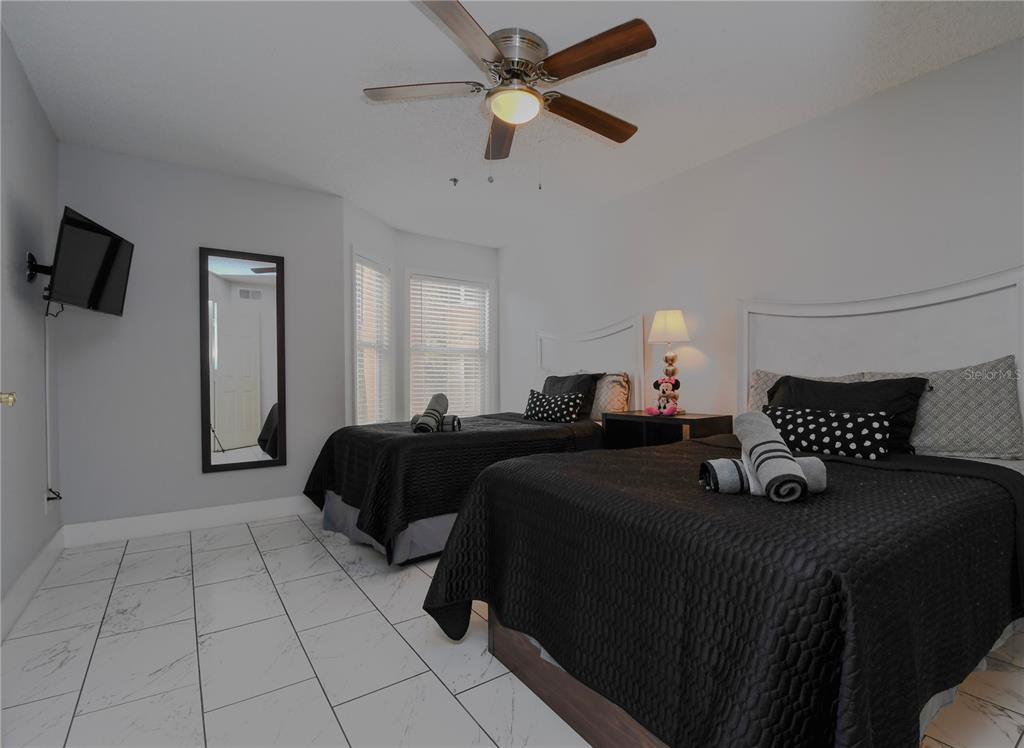 A bedroom features two beds with black bedding, white headboards, and white tiled flooring — 3100 PARKWAY BOULEVARD UNIT 315, KISSIMMEE, FL