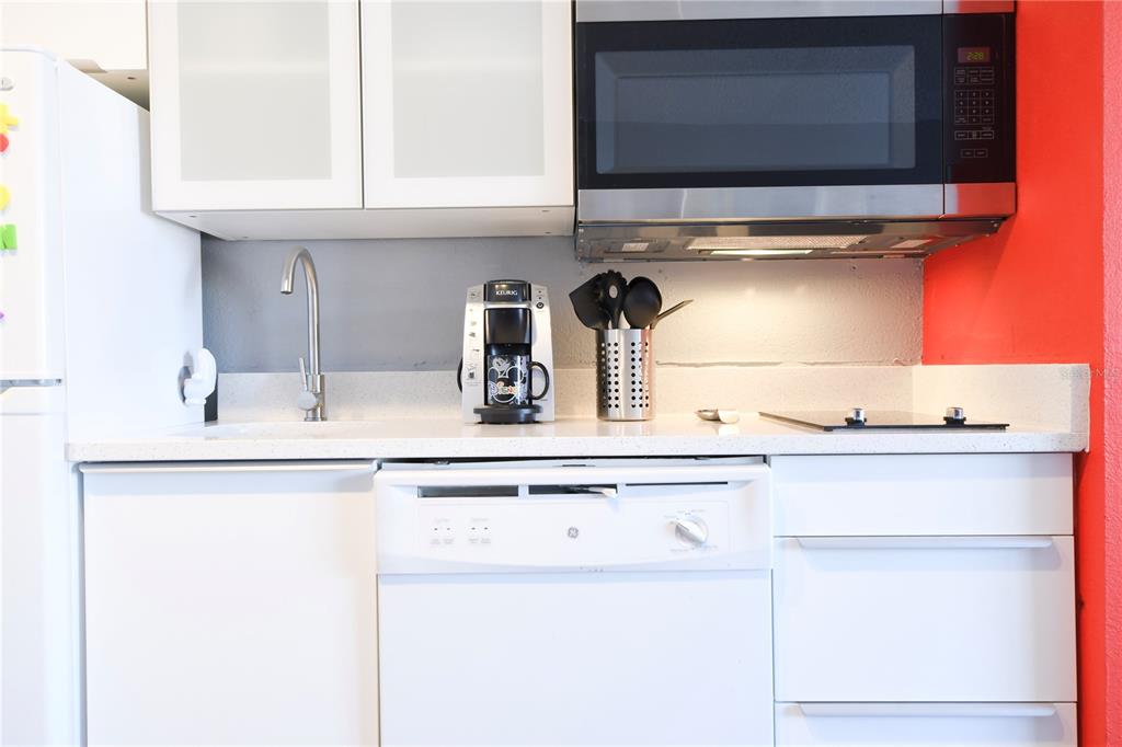 A kitchen features white cabinets, a stainless steel microwave, a dishwasher, and a coffee maker — 3100 PARKWAY BOULEVARD UNIT 315, KISSIMMEE, FL
