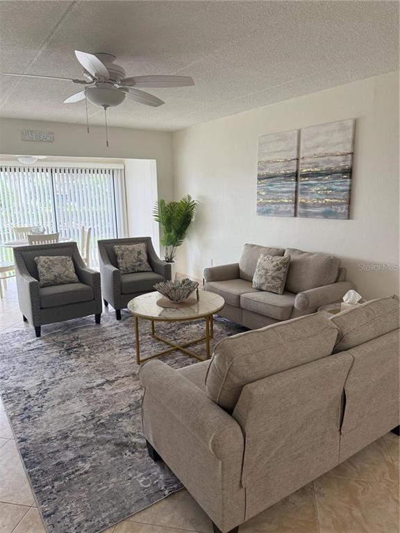 A living room features a sofa, two armchairs, a coffee table, and a large rug — 845 S GULFVIEW BOULEVARD UNIT 110, CLEARWATER BEACH, FL