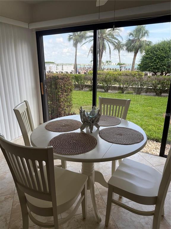 A dining area with a round white table and chairs overlooks a grassy yard and water — 845 S GULFVIEW BOULEVARD UNIT 110, CLEARWATER BEACH, FL