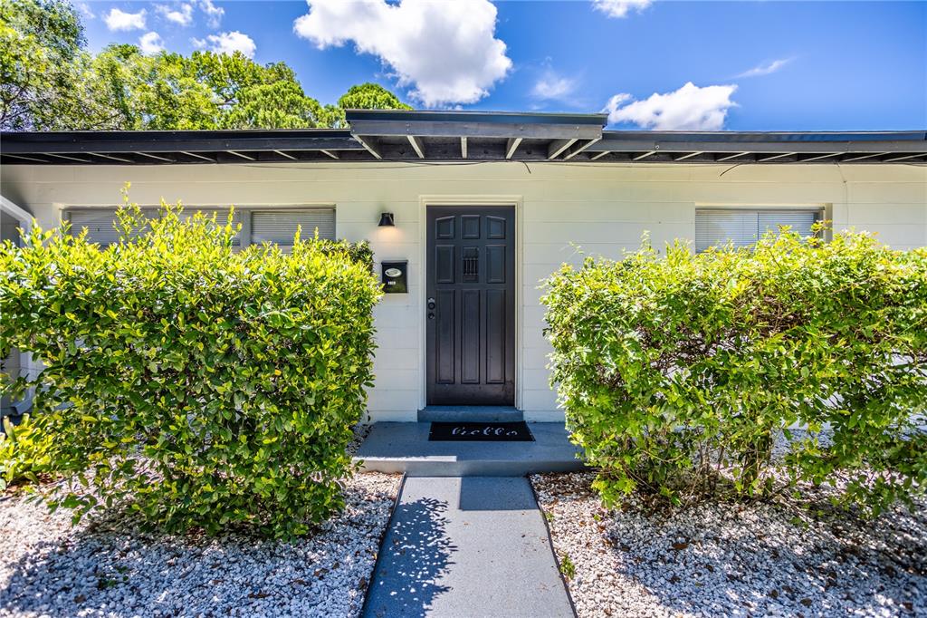 A front exterior view shows a dark door centered between two large green bushes — 1213 CORBETT LANE, ORLANDO, FL