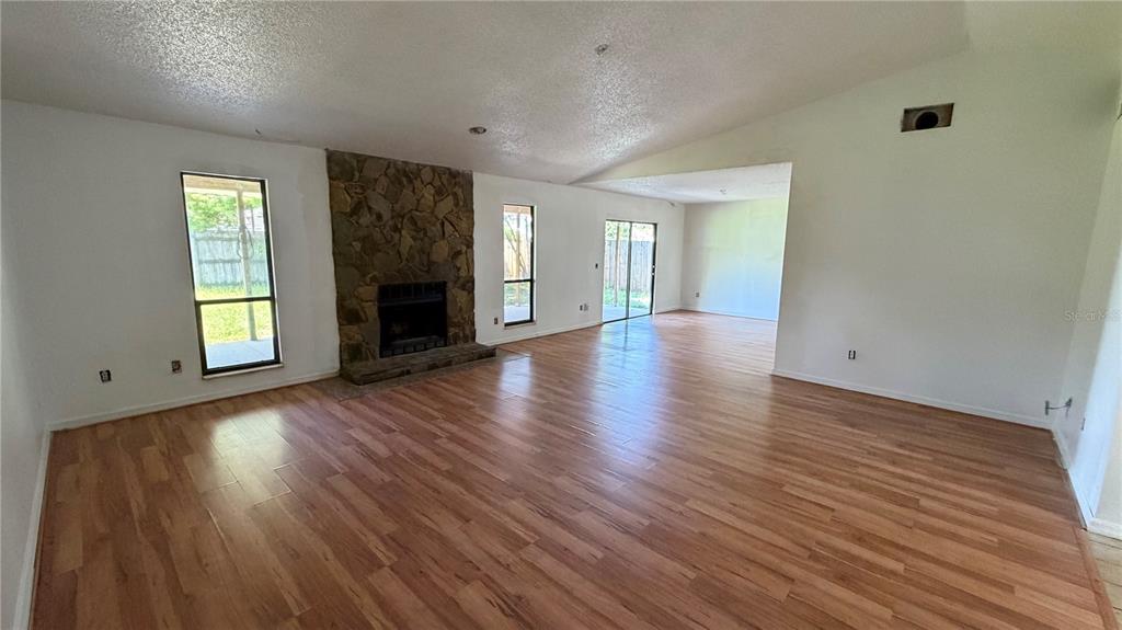 A living room features wood-look flooring, a stone fireplace, and sliding glass doors — 7420 BURNWAY DRIVE, ORLANDO, FL