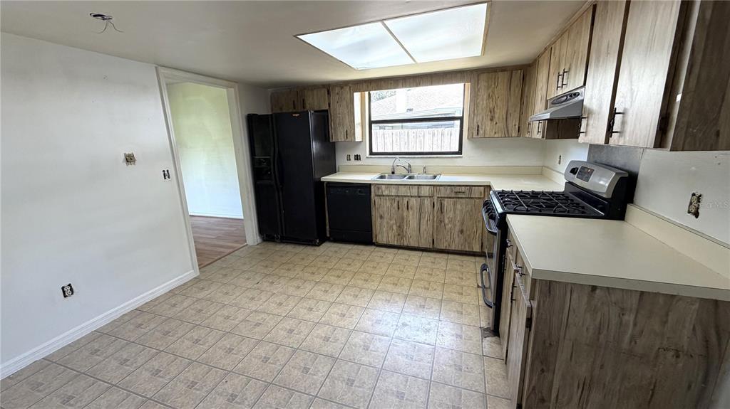 A kitchen features wood-grain cabinets, black appliances, a double sink, and tiled flooring — 7420 BURNWAY DRIVE, ORLANDO, FL