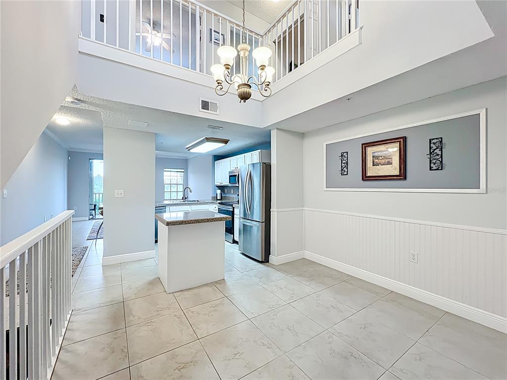 A bright, open-concept kitchen and dining area features tile flooring, a small island, and lofted ceilings — 5459 BENTGRASS DRIVE UNIT 2-116, SARASOTA, FL
