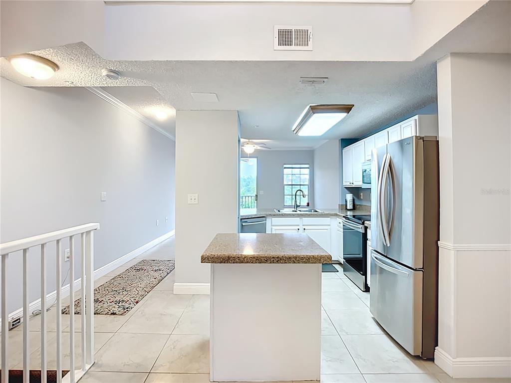 A kitchen with white cabinets, stainless steel appliances, and a central island with granite countertops — 5459 BENTGRASS DRIVE UNIT 2-116, SARASOTA, FL