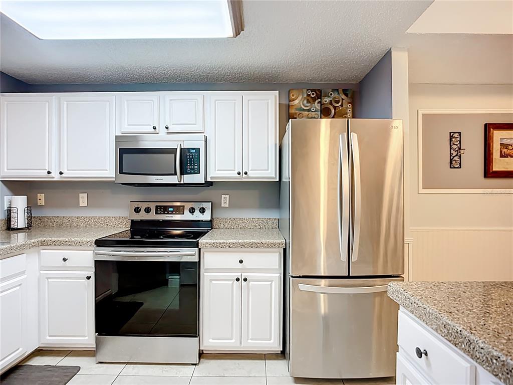 A kitchen features white cabinets, stainless steel appliances, and speckled granite countertops — 5459 BENTGRASS DRIVE UNIT 2-116, SARASOTA, FL