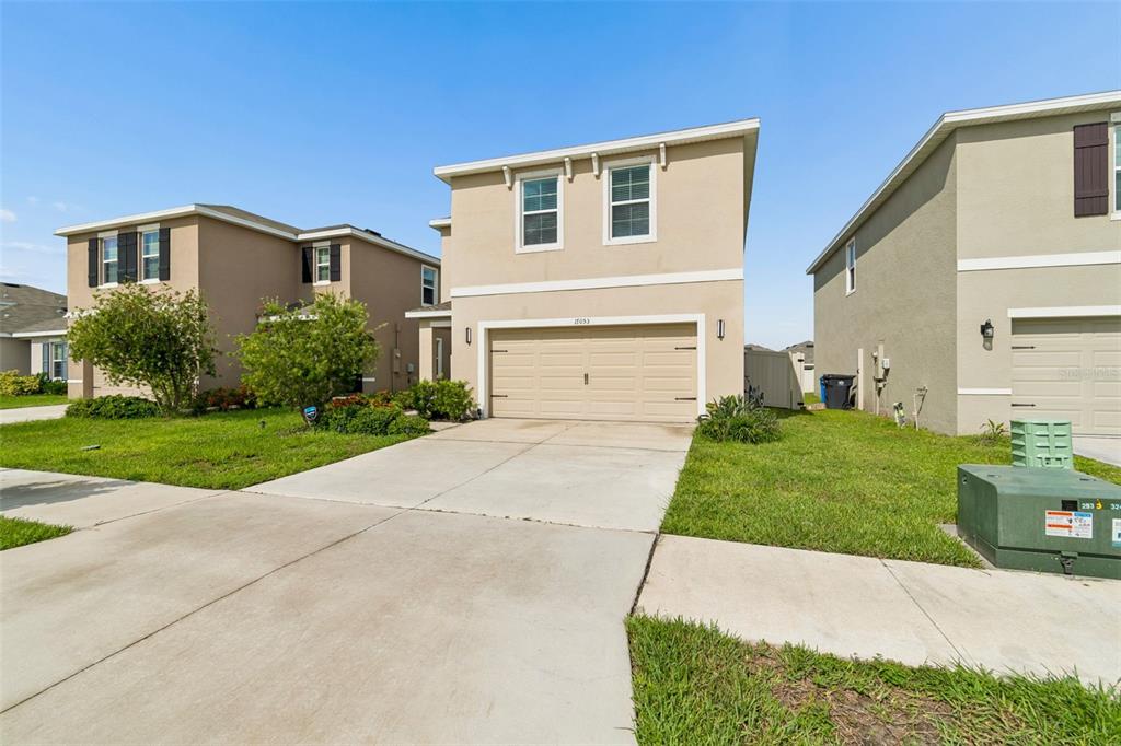 A two-story suburban house with a beige exterior and a two-car garage — 17053 OVAL RUM DRIVE, WIMAUMA, FL