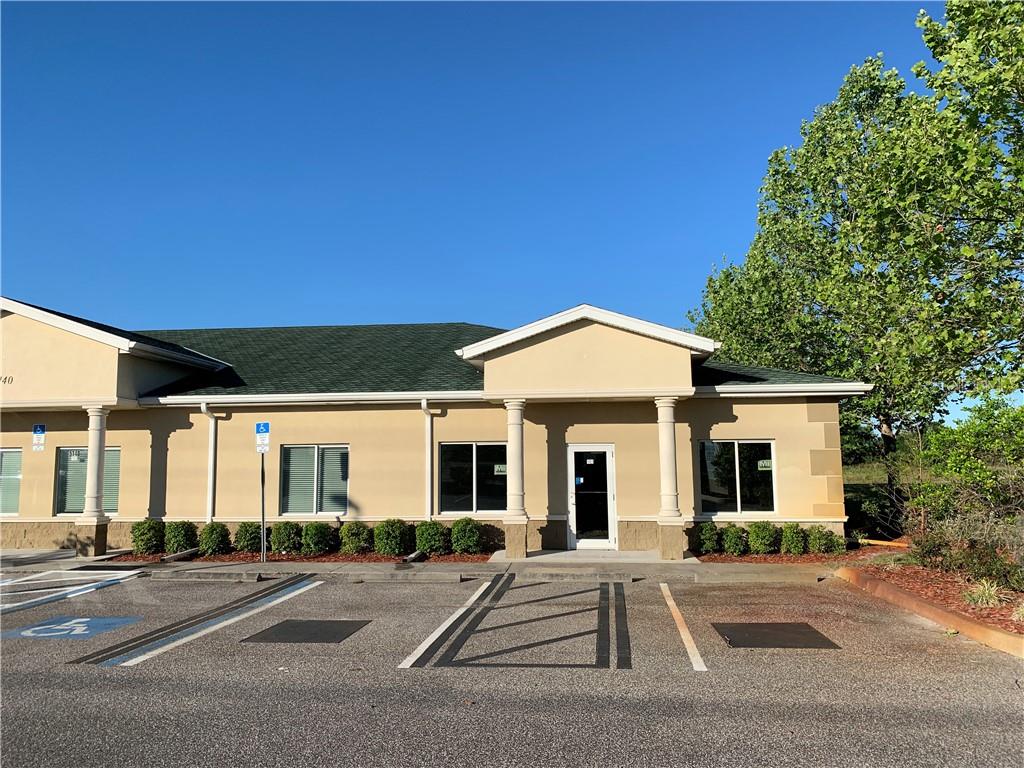 A single-story commercial building with a tan stucco exterior and a dark shingled roof — 5140 DEER PARK DRIVE, NEW PORT RICHEY, FL