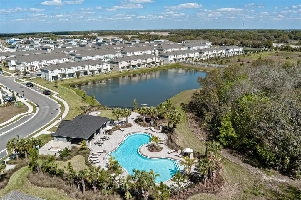 An aerial view shows a community swimming pool, clubhouse, and pond surrounded by residential townhomes — 6106 FAIRMONT LANE, PALMETTO, FL
