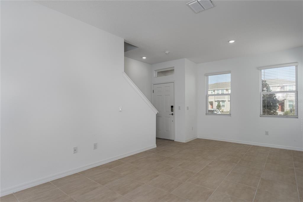 An empty room with white walls, tile flooring, a front door, and two windows — 6106 FAIRMONT LANE, PALMETTO, FL