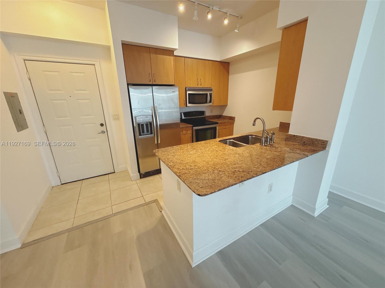 A kitchen features light wood cabinets, granite countertops, stainless steel appliances, and tile flooring — 1830 Radius Dr # 1121, Hollywood FL 33020, HOLLYWOOD, FL