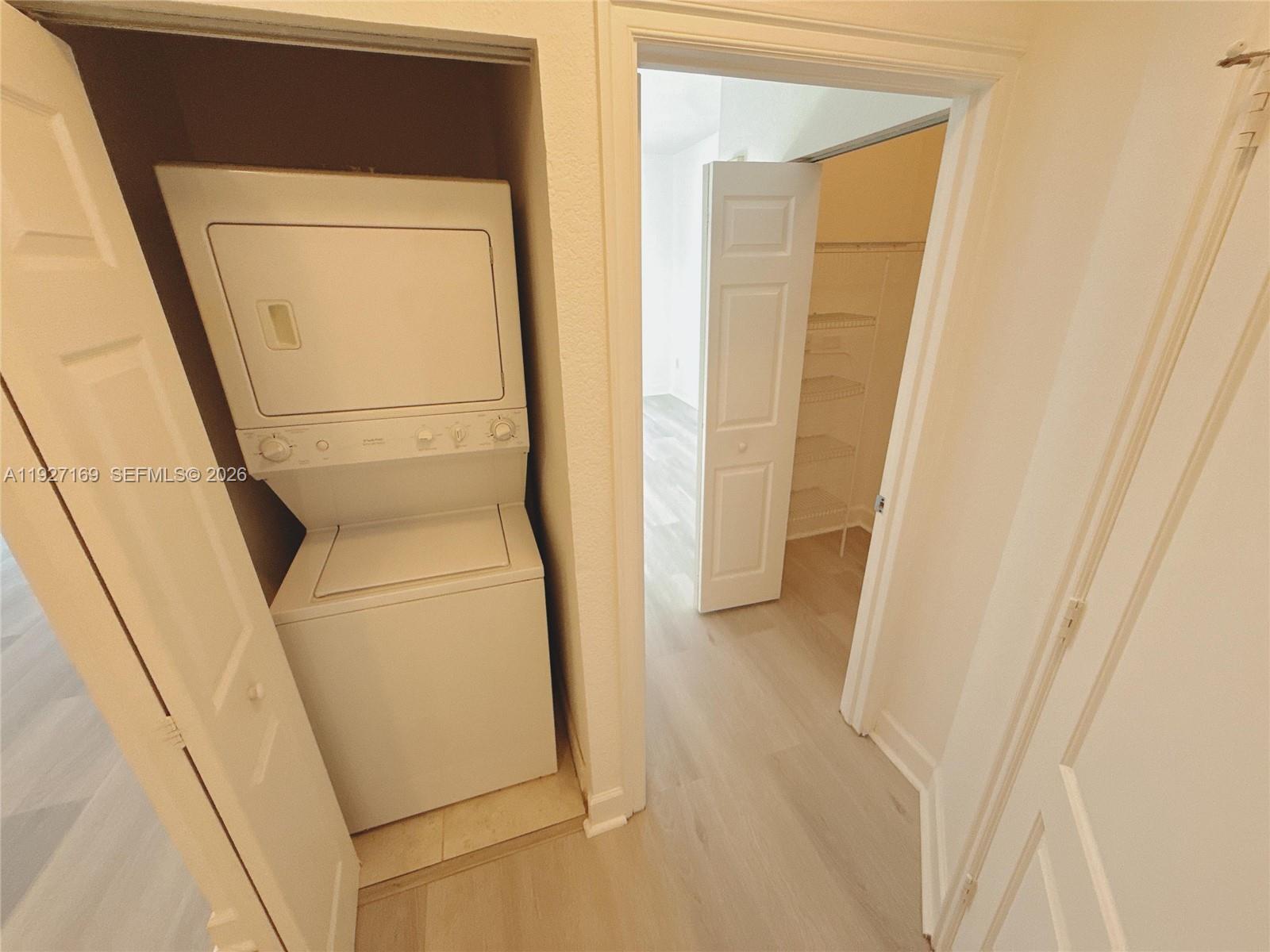 A stacked washer and dryer unit sits in a closet next to a walk-in closet — 1830 Radius Dr # 1121, Hollywood FL 33020, HOLLYWOOD, FL