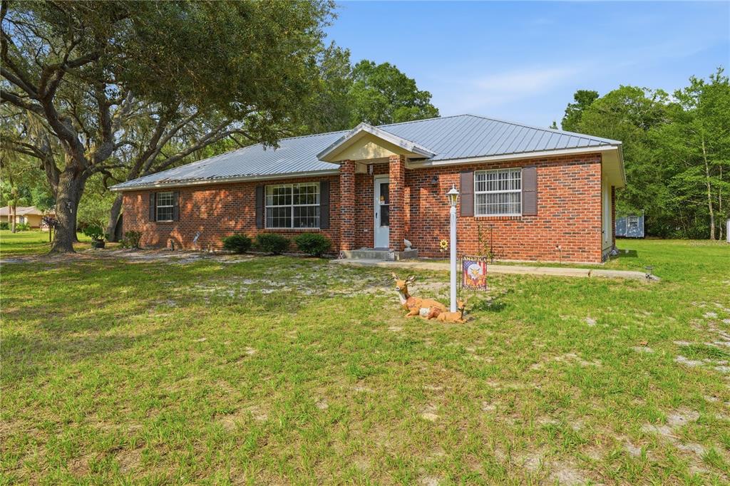 A single-story brick house with a metal roof sits on a grassy lot — 5480 NE 53RD TERRACE, HIGH SPRINGS, FL