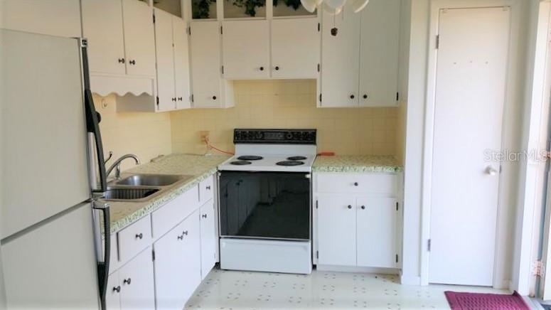A kitchen features white cabinets, a white refrigerator, a freestanding stove, and light-colored countertops — 608 LEMON STREET, AUBURNDALE, FL