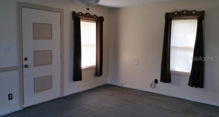 A room with gray carpet, two windows with brown curtains, and a white entry door — 608 LEMON STREET, AUBURNDALE, FL