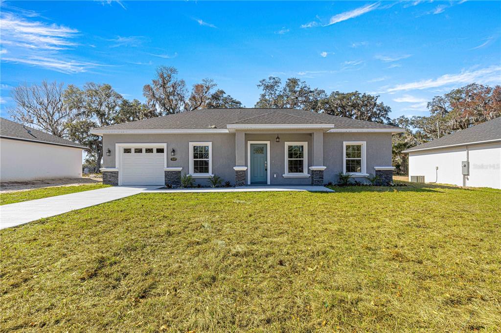 A single-story gray house with a teal front door, white trim, and a concrete driveway — 15223 SE 61ST COURT, SUMMERFIELD, FL
