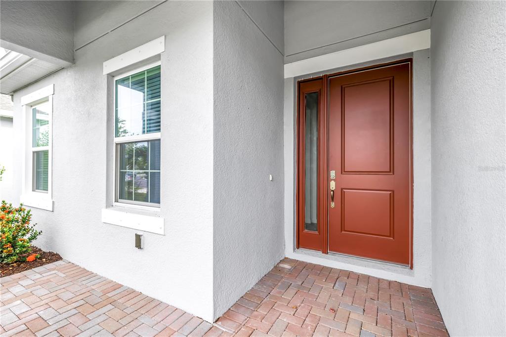 A red front door with a side window sits on a brick porch — 11332 GALLATIN TRAIL, PARRISH, FL