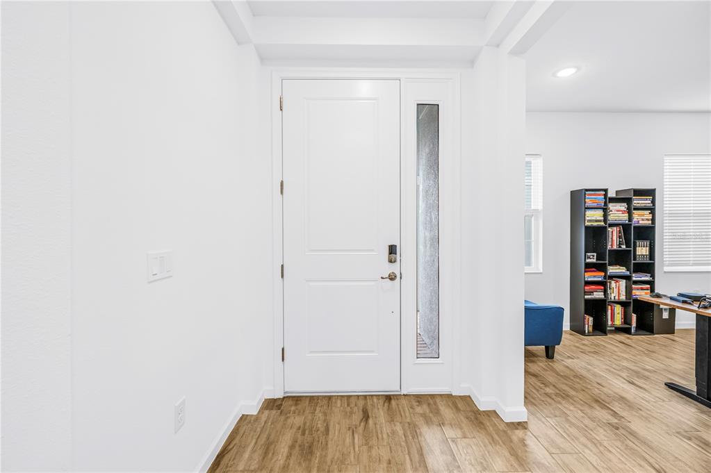An entryway features a white front door with a side window and wood-look flooring — 11332 GALLATIN TRAIL, PARRISH, FL