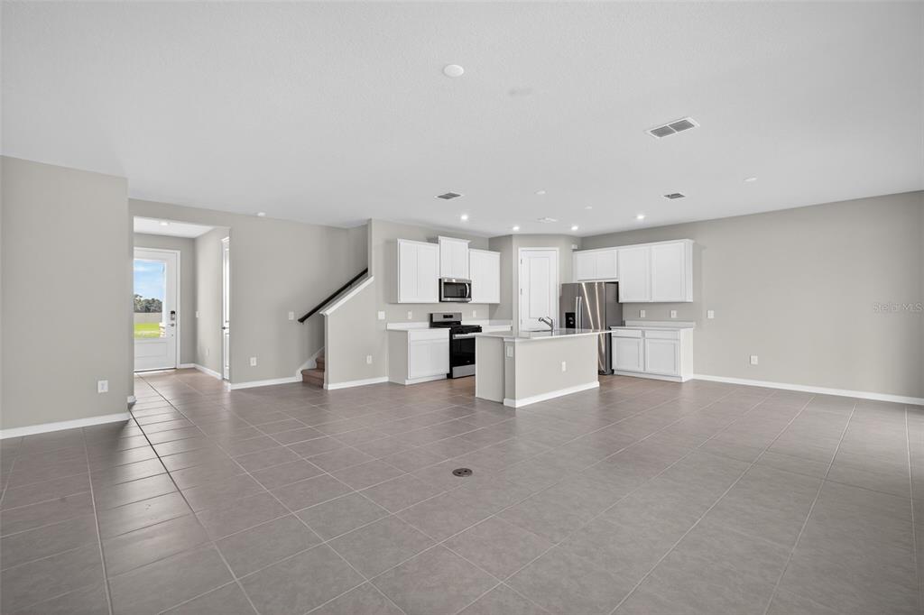 An open-concept kitchen with white cabinets, stainless steel appliances, and tile flooring — 13014 SUNSEED STREET, PARRISH, FL