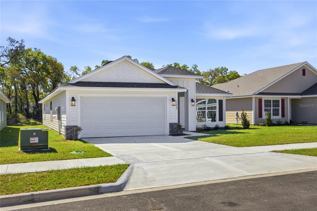 A single-story house with a white garage, vertical siding, and a concrete driveway — 13634 NW 150TH CIRCLE, ALACHUA, FL
