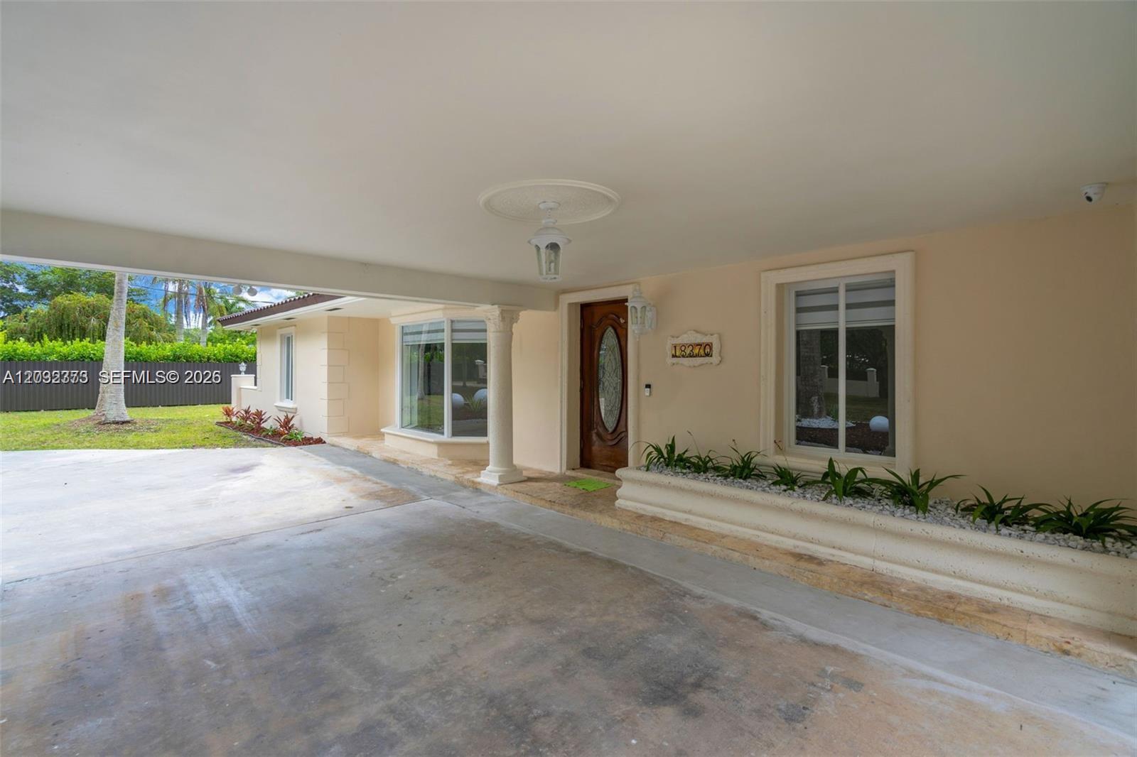 A covered entryway features a concrete driveway, a front door, and a long planter box — 18370 SW 212th St, Miami FL 33187, MIAMI, FL