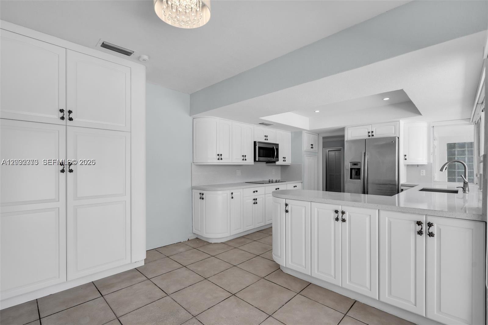 A white kitchen features stainless steel appliances, light countertops, and tile flooring — 18370 SW 212th St, Miami FL 33187, MIAMI, FL