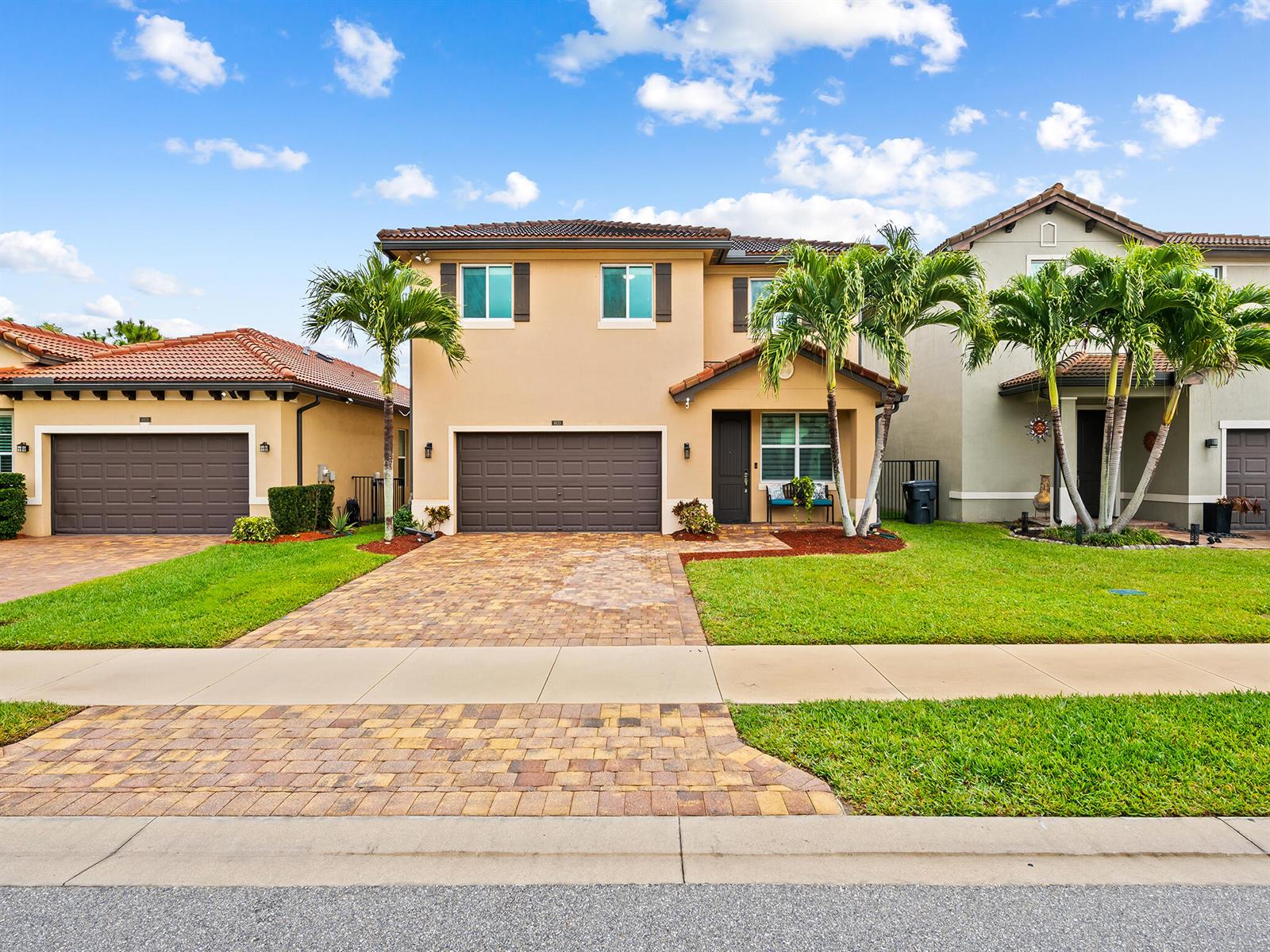 A two-story tan house with a brown garage and palm trees in the front yard — 6830 Langdon Way, Lake Worth FL 33463, LAKE WORTH, FL