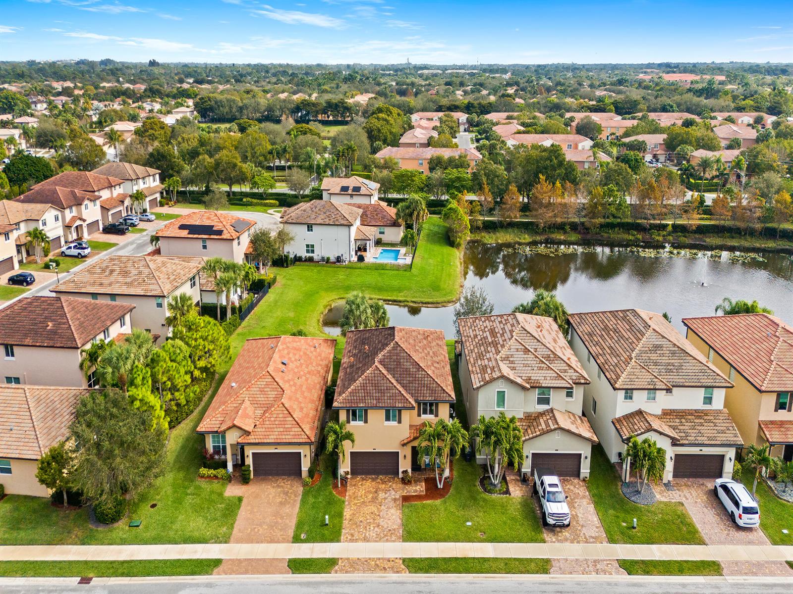An aerial view shows a suburban neighborhood with houses, a pond, and paved driveways — 6830 Langdon Way, Lake Worth FL 33463, LAKE WORTH, FL