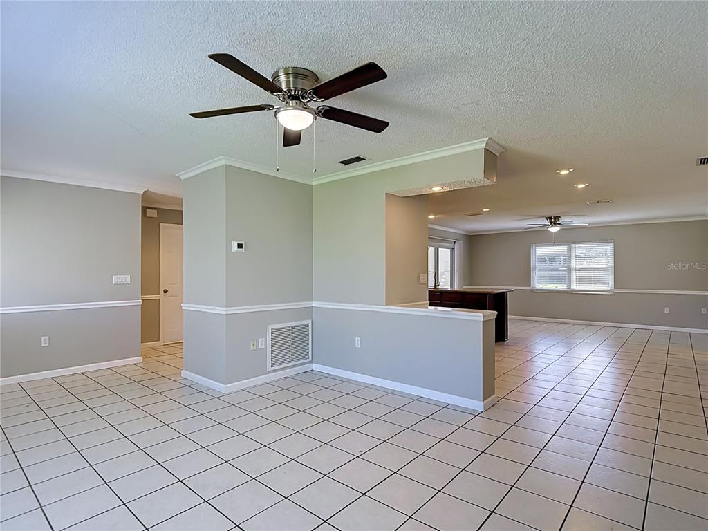 An open-concept living area features light gray walls, white chair rail molding, and white tile flooring — 13065 PIRATE LANE, SPRING HILL, FL