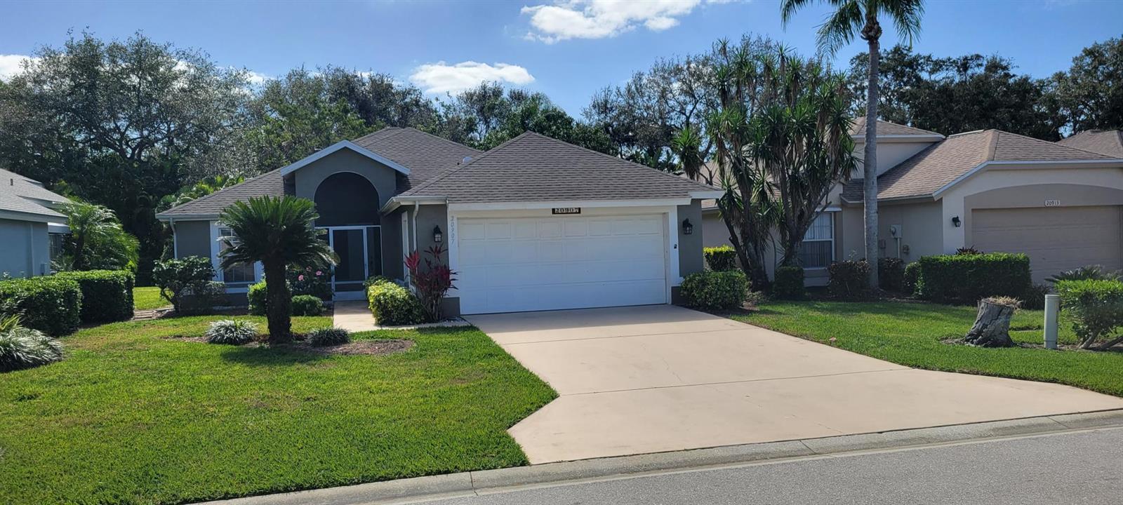 A single-story suburban house with a two-car garage, concrete driveway, and landscaped front yard — 20907 Country Barn Drive, FL 33928, FL