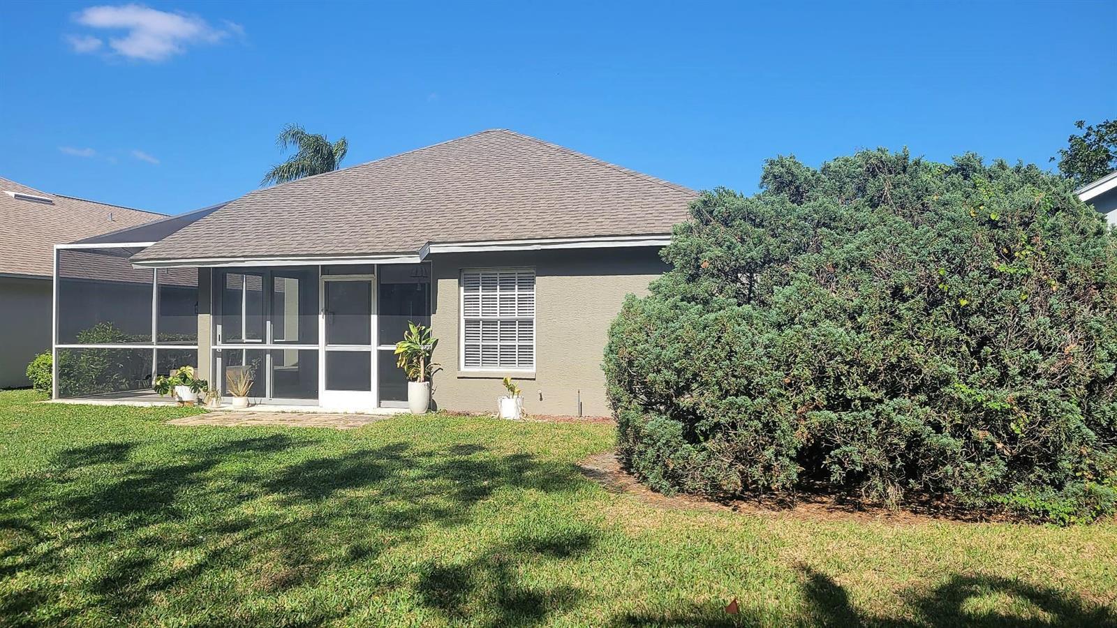 The exterior of a house features a screened-in patio, a single window, and a large bush — 20907 Country Barn Drive, FL 33928, FL